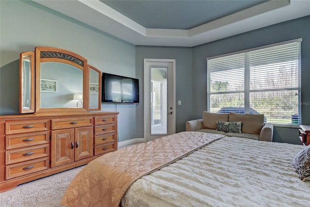 bedroom featuring a raised ceiling, light carpet, and access to outside