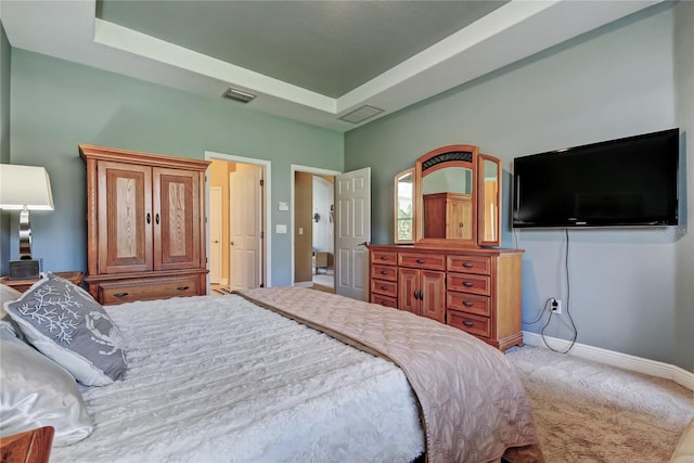 bedroom featuring visible vents, light colored carpet, baseboards, and a tray ceiling