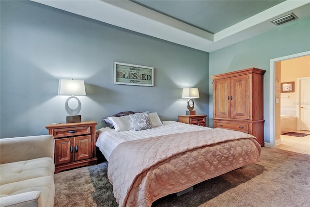 bedroom with visible vents, light carpet, and ensuite bathroom