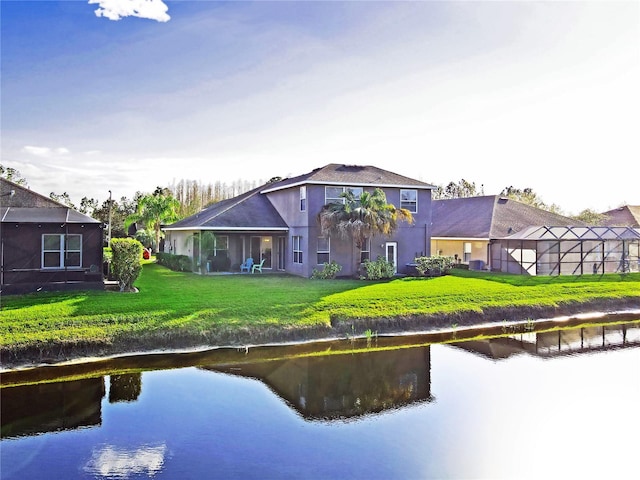 rear view of house with a yard, a water view, and stucco siding