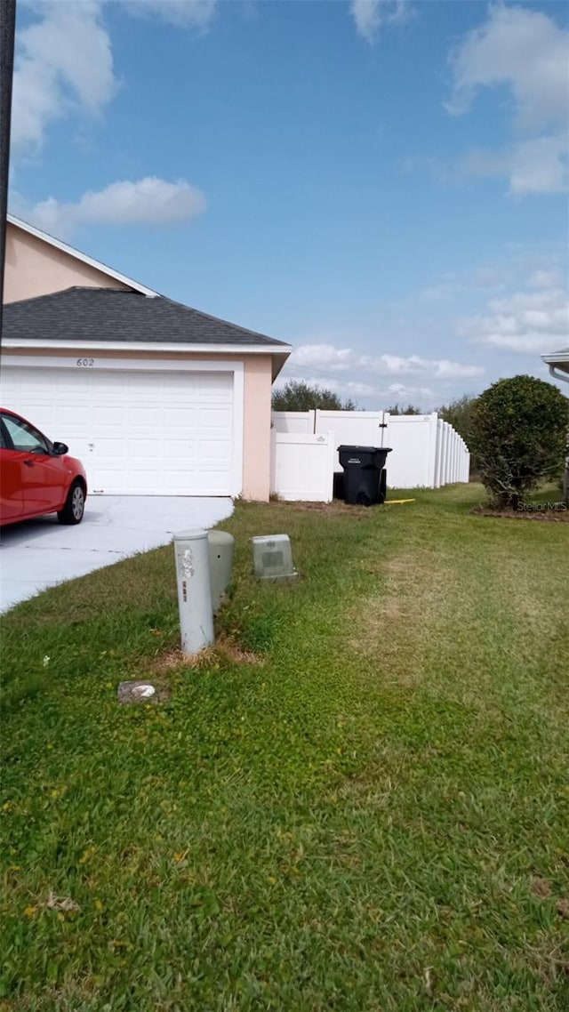 garage with concrete driveway and fence