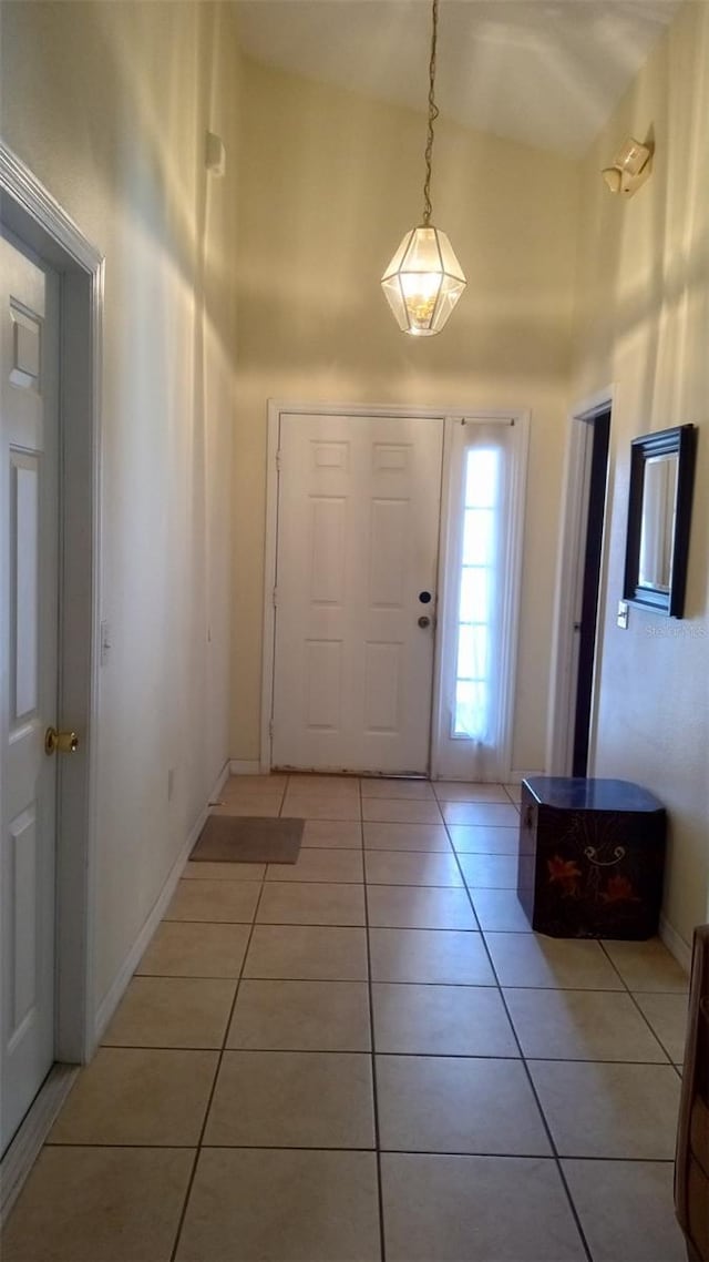 foyer entrance with light tile patterned floors, baseboards, and a towering ceiling