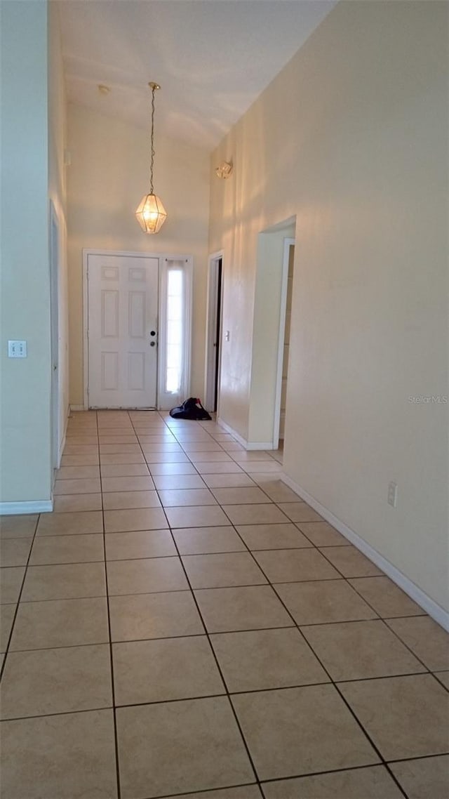 entrance foyer with light tile patterned floors, baseboards, and a high ceiling