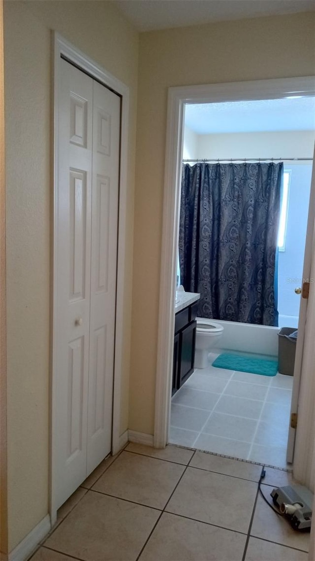 bathroom with vanity, a closet, toilet, tile patterned flooring, and shower / tub combo with curtain