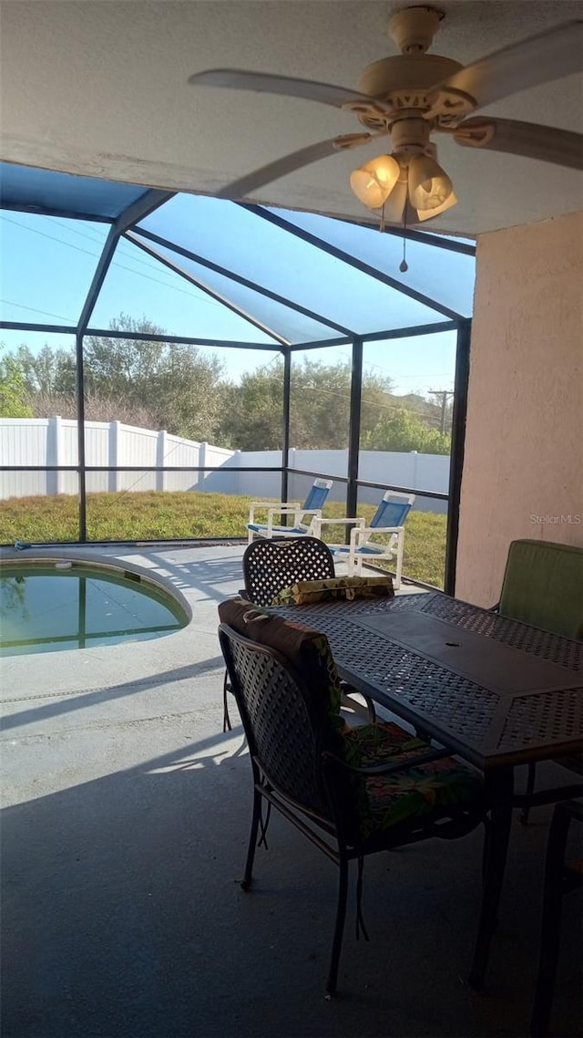 view of patio / terrace featuring outdoor dining area, a fenced in pool, a fenced backyard, a ceiling fan, and glass enclosure