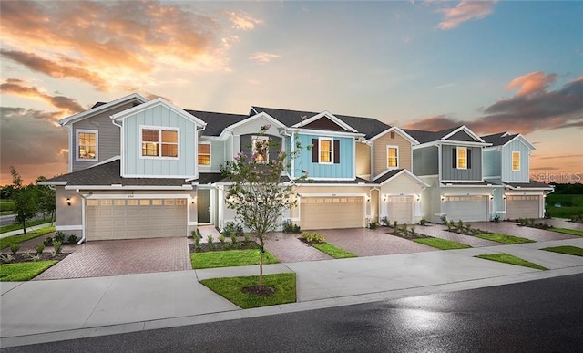 townhome / multi-family property featuring a garage, decorative driveway, and board and batten siding