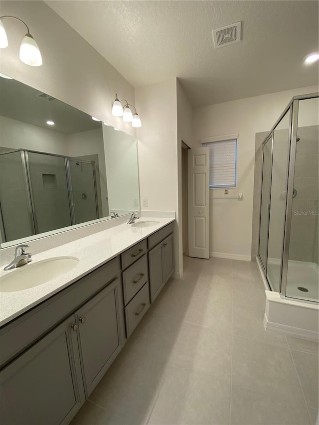 bathroom with visible vents, a stall shower, a sink, a textured ceiling, and double vanity