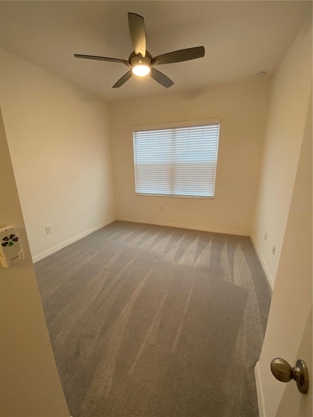 carpeted spare room with baseboards and a ceiling fan