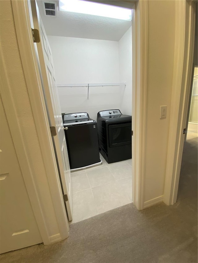 laundry area featuring light tile patterned floors, laundry area, visible vents, and separate washer and dryer