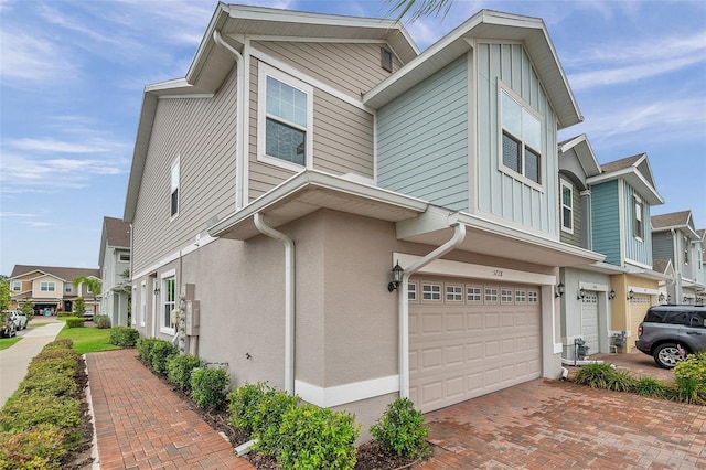 5728 Skytop Dr, Lithia, FL 33547 - view of side of home with a garage, a residential view, decorative driveway, and stucco siding