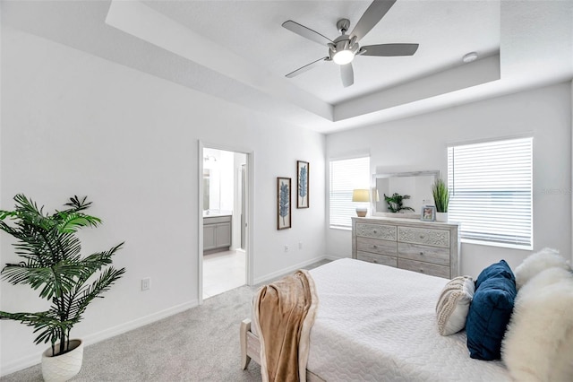 5728 Skytop Dr, Lithia, FL 33547 - bedroom featuring a tray ceiling, light colored carpet, baseboards, ensuite bath, and ceiling fan