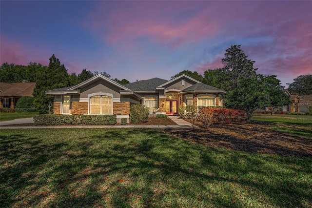 view of front of home featuring stone siding, stucco siding, and a front yard