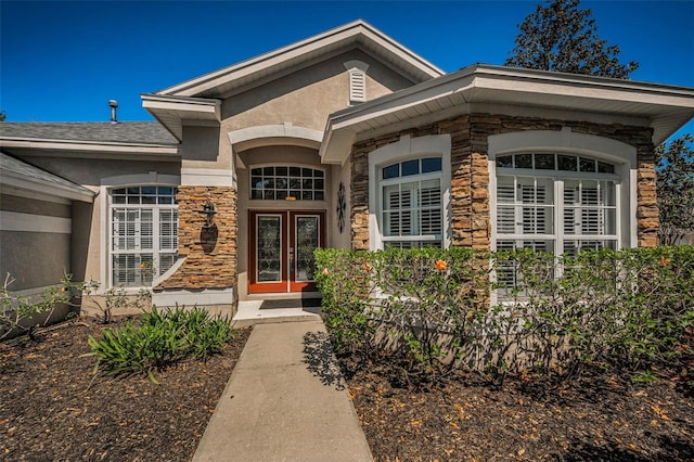 property entrance with stucco siding, stone siding, and french doors