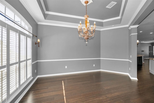 unfurnished dining area with a tray ceiling, a notable chandelier, wood finished floors, and visible vents