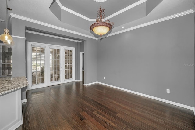 spare room featuring dark wood finished floors, baseboards, a tray ceiling, and ornamental molding