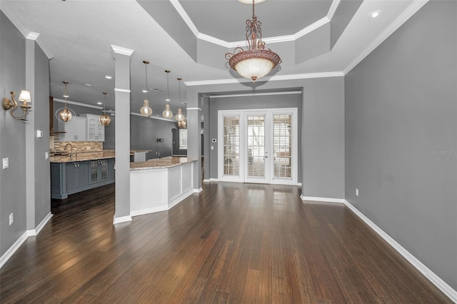 kitchen featuring dark wood finished floors, a tray ceiling, crown molding, and tasteful backsplash