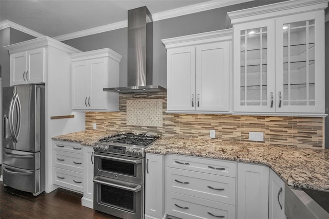 kitchen with glass insert cabinets, crown molding, stainless steel appliances, white cabinetry, and wall chimney exhaust hood