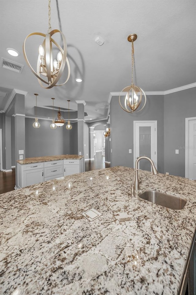 kitchen featuring visible vents, ornamental molding, a sink, white cabinetry, and an inviting chandelier