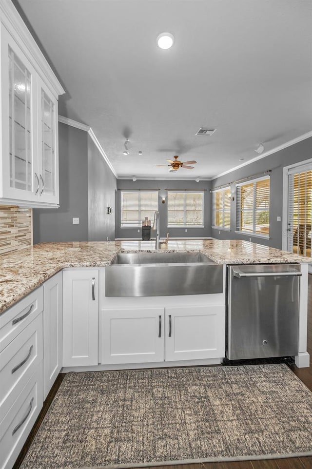 kitchen with visible vents, a sink, white cabinets, stainless steel dishwasher, and crown molding