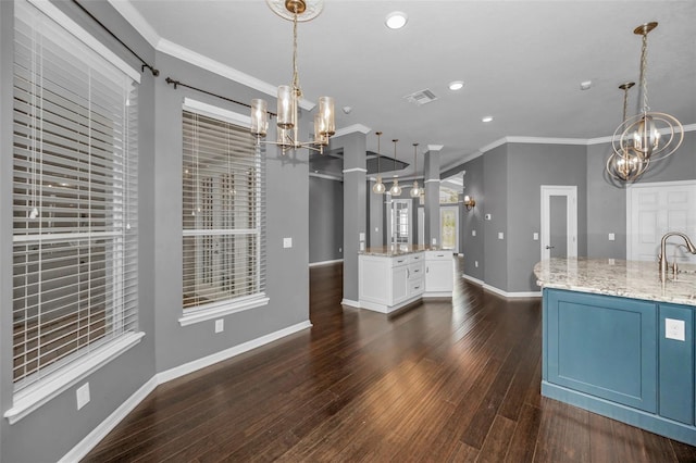 kitchen featuring dark wood-type flooring, crown molding, baseboards, light stone countertops, and a notable chandelier