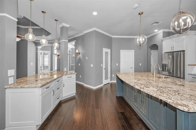 kitchen with stainless steel fridge with ice dispenser, arched walkways, a large island with sink, and a sink