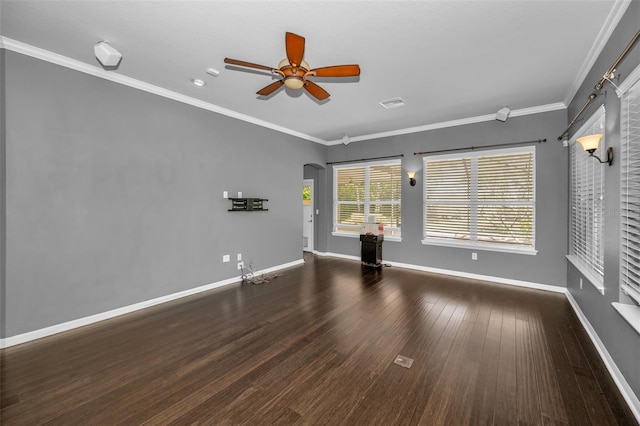 empty room featuring wood finished floors, arched walkways, ornamental molding, and a ceiling fan