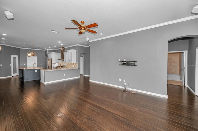 unfurnished living room featuring a ceiling fan, dark wood finished floors, recessed lighting, arched walkways, and baseboards