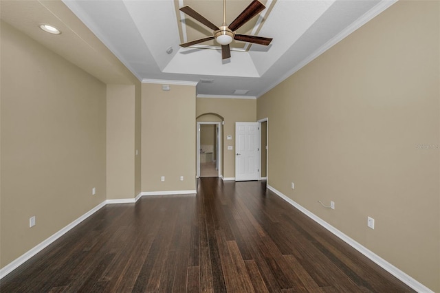 unfurnished room with dark wood-type flooring, baseboards, arched walkways, a raised ceiling, and a ceiling fan