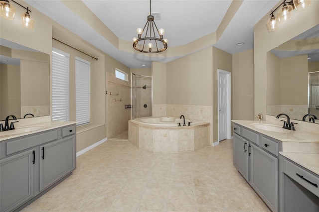 bathroom with an inviting chandelier, a garden tub, a tile shower, and a sink