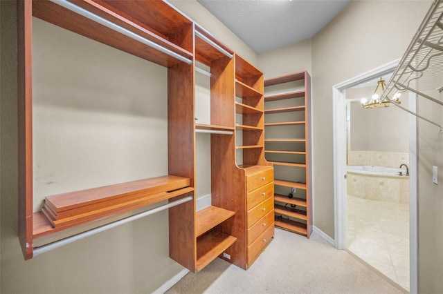 walk in closet featuring a notable chandelier and carpet floors