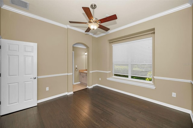 empty room featuring visible vents, ornamental molding, wood finished floors, arched walkways, and ceiling fan