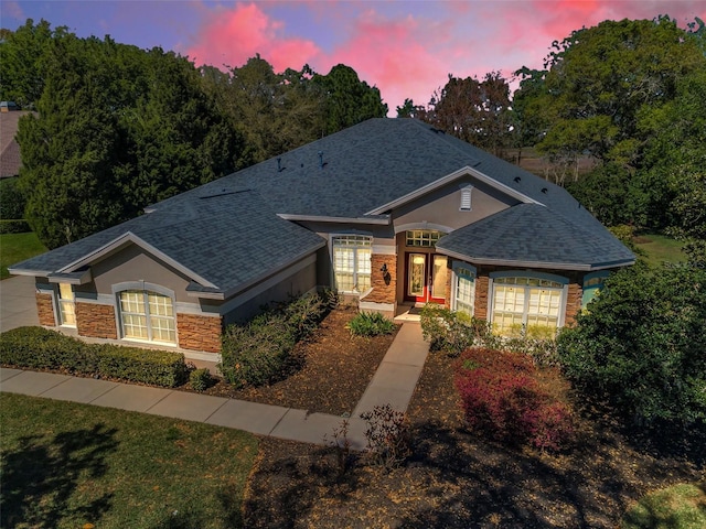 single story home featuring stone siding, stucco siding, and roof with shingles