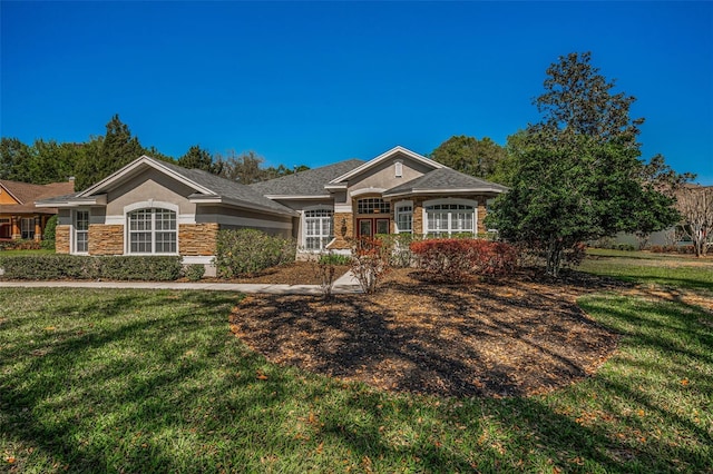 view of front of house featuring a front yard, stone siding, and stucco siding