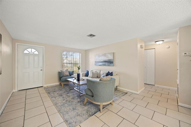 living area with light tile patterned flooring, visible vents, a textured ceiling, and baseboards