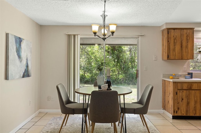 dining space featuring an inviting chandelier, light tile patterned floors, baseboards, and a textured ceiling