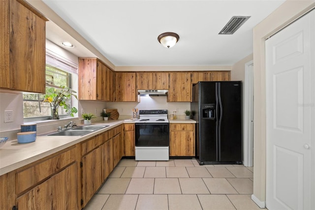 kitchen featuring visible vents, a sink, under cabinet range hood, range with electric stovetop, and black fridge