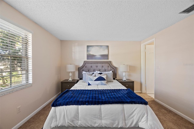 carpeted bedroom featuring visible vents, a textured ceiling, and baseboards