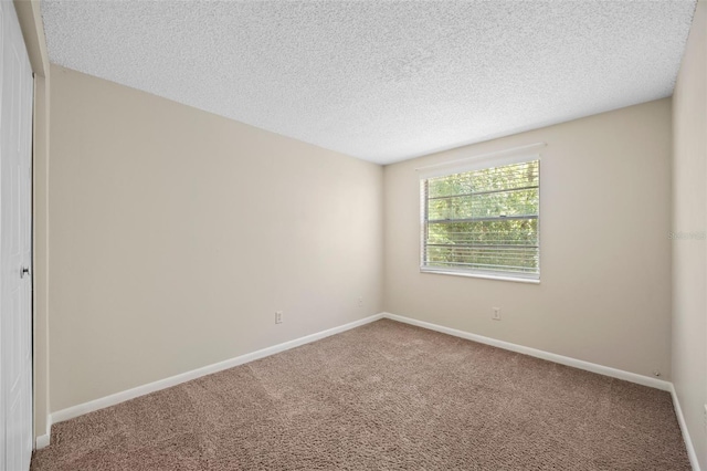 carpeted spare room featuring baseboards and a textured ceiling