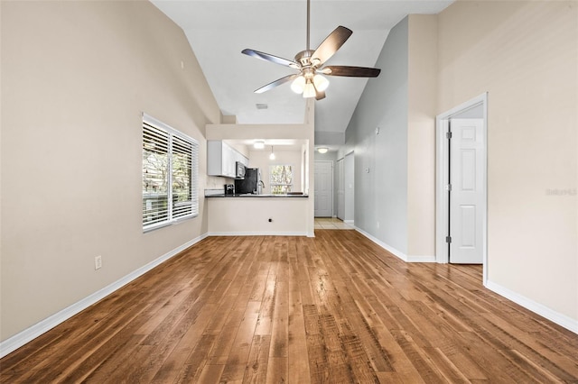 unfurnished living room with baseboards, high vaulted ceiling, wood finished floors, and a ceiling fan