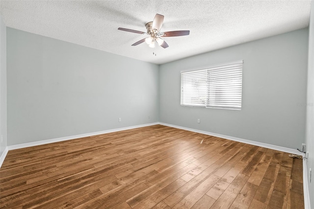 empty room with hardwood / wood-style flooring, a ceiling fan, baseboards, and a textured ceiling