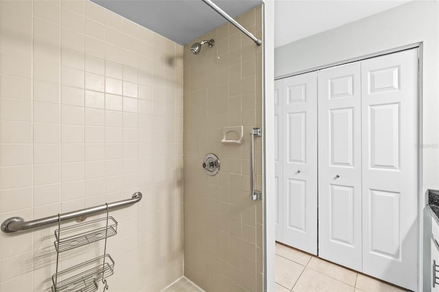 full bath featuring tile patterned flooring, a stall shower, and a closet