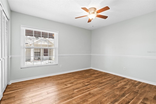 empty room with baseboards, a textured ceiling, a ceiling fan, and hardwood / wood-style floors