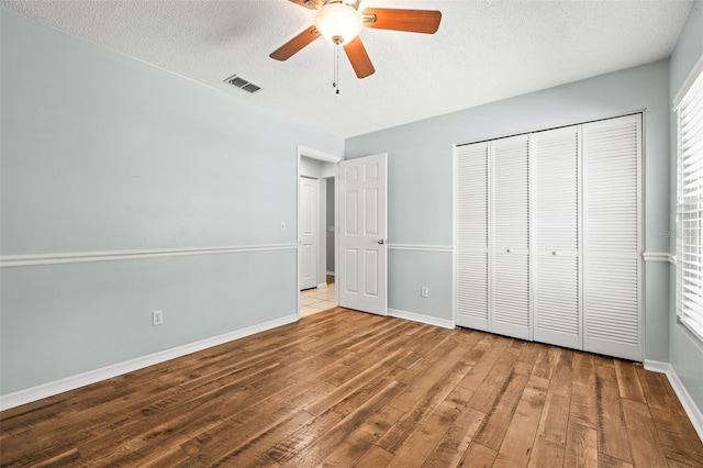 unfurnished bedroom with hardwood / wood-style flooring, baseboards, visible vents, and a textured ceiling