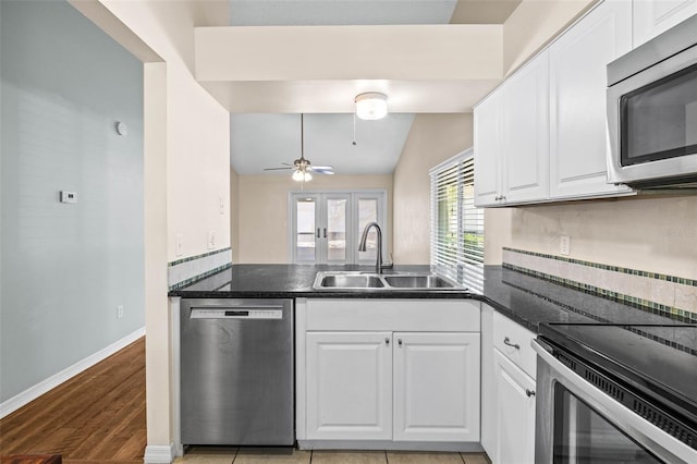 kitchen featuring a sink, stainless steel appliances, dark countertops, and white cabinetry