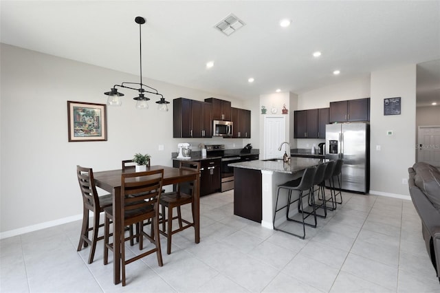 kitchen with visible vents, dark brown cabinets, a breakfast bar area, appliances with stainless steel finishes, and a sink