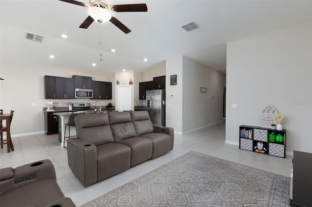 living area featuring light tile patterned floors, visible vents, baseboards, and a ceiling fan