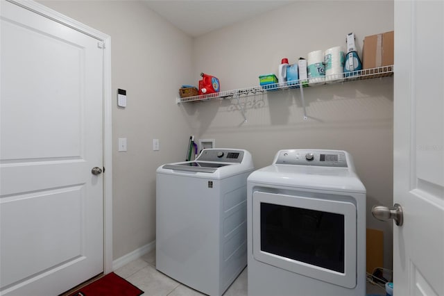 washroom with washer and dryer, laundry area, light tile patterned floors, and baseboards