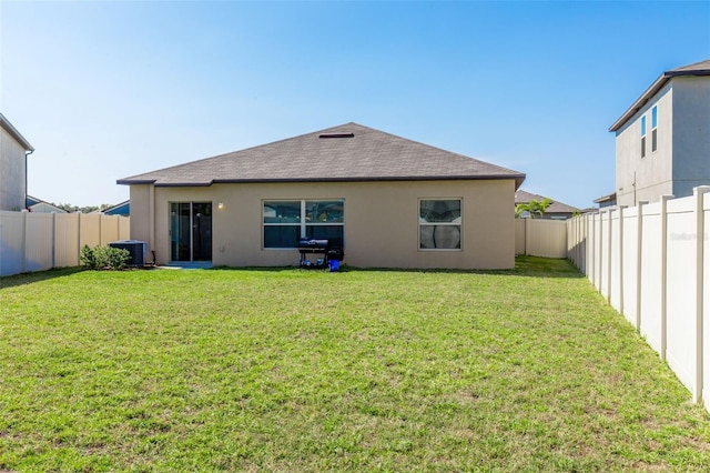 back of property with stucco siding, a lawn, and a fenced backyard