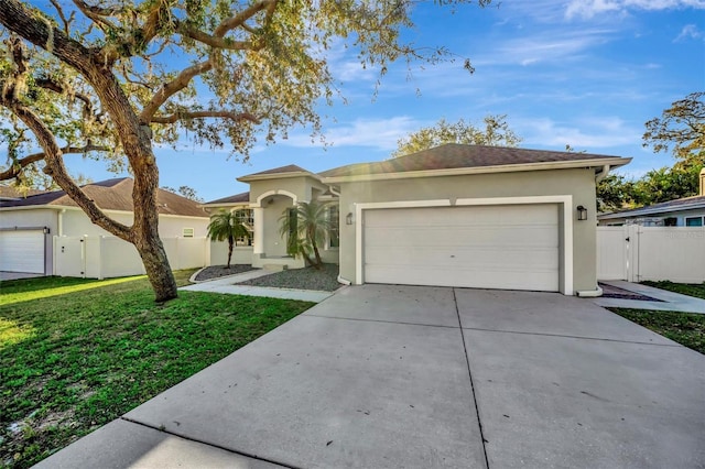 ranch-style house featuring fence, a front yard, driveway, an attached garage, and a gate