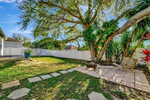 view of yard with a fenced backyard, a fire pit, and a patio